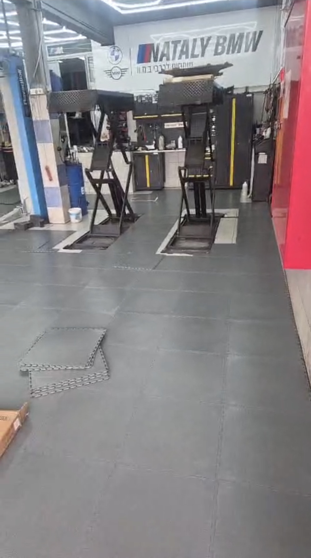 אזור העבודה במוסך עם רצפת PVC אפורה חדשה ושתי עמדות הרמה
